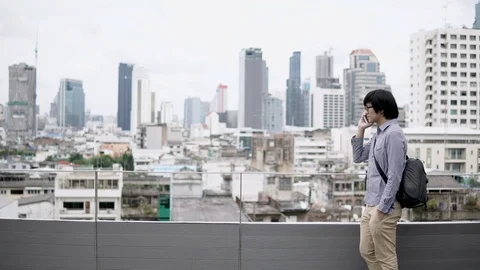 Asian businessman using smartphone for business talk walking on rooftop Stock-Footage 91015953