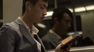Asian Businessman In Wireless Earphones Using Cellphone In Subway Train Stock Footage