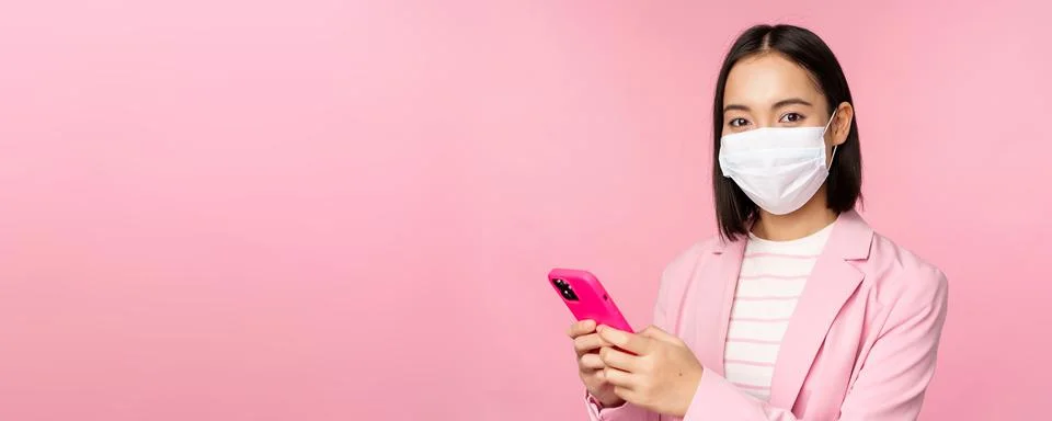 Asian businesswoman in medical face mask using mobile phone. Japenese saleswoman Stock Photos