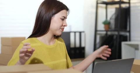 Asian businesswoman smiling while preparing parcel boxes for shipping, updating Stock Footage 330840468