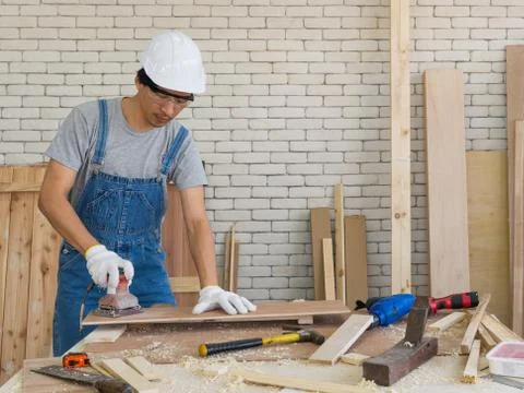 Asian carpenter use a sander machine to smooth plywood surfaces Stock Photos