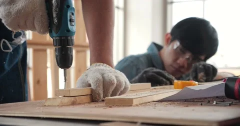 Asian carpenter uses a hand drill to assemble the wood in the carpentry shop. 動画素材 162826539