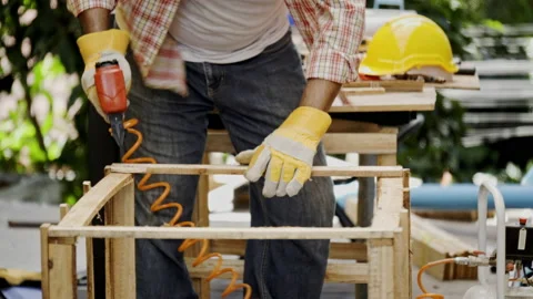 Asian carpenter worker wearing protective gloves is using power drill assembling Stock Footage 228944045