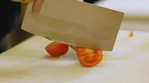 Asian chef cuts red tomatoes. Stockbeeldmateriaal 104335299