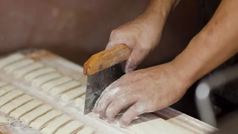 Asian Chef Slicing Dough Strips with Bench Scraper in Bakery Stock Footage 339124117