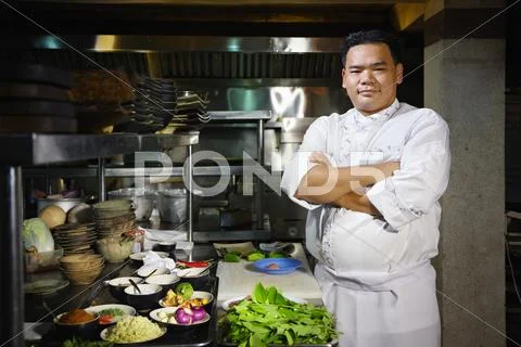 Asian chef smiling at camera in restaurant kitchen Stock-Fotos