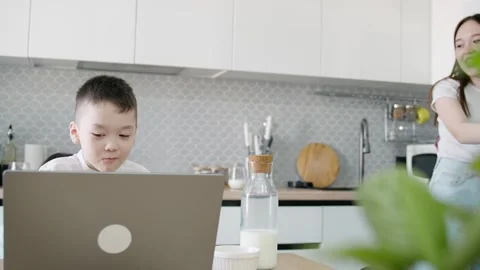 An Asian child doing his homework on a laptop in the kitchen Stock Footage 276409716
