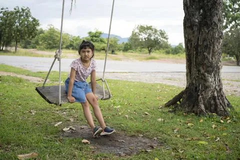 Asian child sitting on a rope swing under tree Stockfoto's