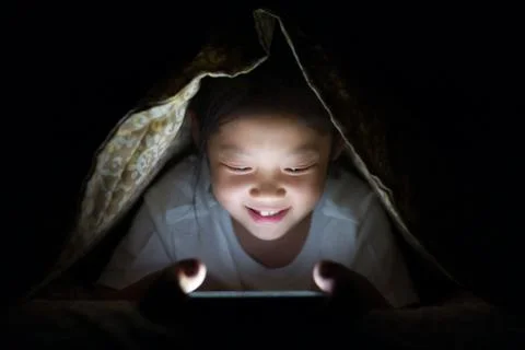 Asian Child Using Tablet PC in Bed at Night Foto stock