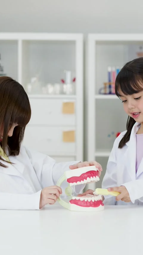 Asian Children in Lab Coats Learning Dental Hygiene with Tooth Model Stock Footage 342313157
