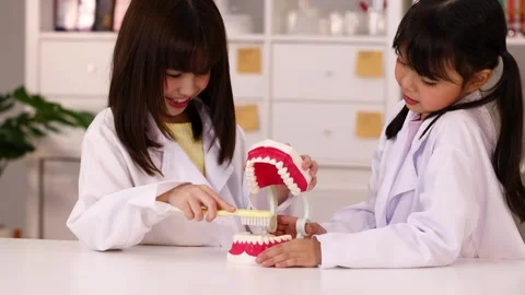 Asian Children in Lab Coats Learning Dental Hygiene with Tooth Model Stock Footage 342313183