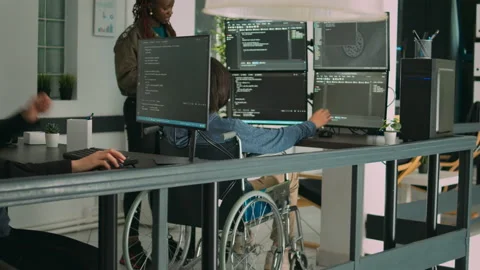 Asian coder with physical disability working with african american developer Stock Footage 220380968