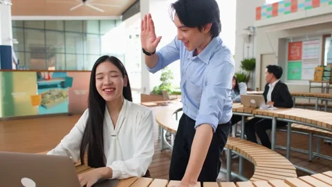Asian Colleagues Collaborating on Laptop and Giving High Five in Office Stock Footage 346018059