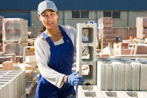 Asian construction shop worker stacks bricks on an open-air site Stock Photos