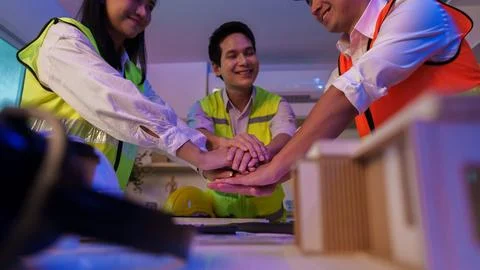 Asian construction team stacking hands together for teamwork and unity Stock Photos