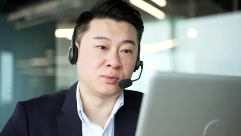 Asian corporate operator in headset working in customer support service  Stock Footage 321889577