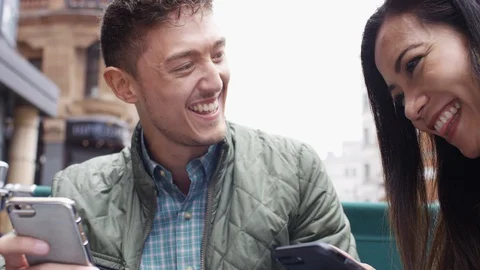 Asian couple at a cafe table using their phones and laughing Stock-Footage 90363030