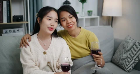 Asian couple happily chatting while relaxing on the sofa together. Видео 316871736