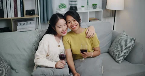 Asian couple happily chatting while relaxing on the sofa together. Vidéo 316873198