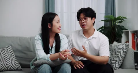 Asian couple having fun talking on the sofa in the living room at home. Stock-Footage 313926776