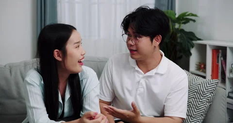 Asian couple having fun talking on the sofa in the living room at home. Stockbeeldmateriaal 313926792
