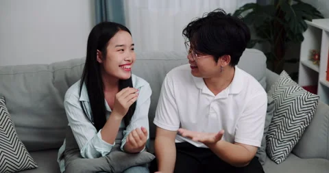 Asian couple having fun talking on the sofa in the living room at home. Stock-Footage 313926980