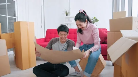 Asian couple planning decorating when moving home looking at the blueprint Stock Footage 152552197
