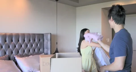 Asian couple seeing DONATIONS box sorting, packing clothing into box on bed to Stock Footage 342019616