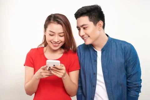 Asian couple using cell smart phone message smile standing on white backgroun Stock Photos