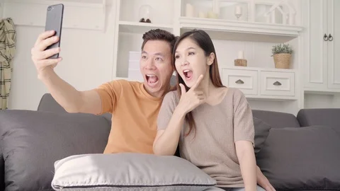 Asian couple using smartphone for selfie in living room at home. Stock Footage 100562441