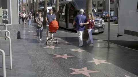 Asian couple walking Walk of Fame father husband pushing stroller Hollywood LA Stock Footage