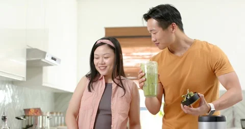 Asian couple watching man checking fresh green smoothie cup and bowl for texture Stock Footage 344948631