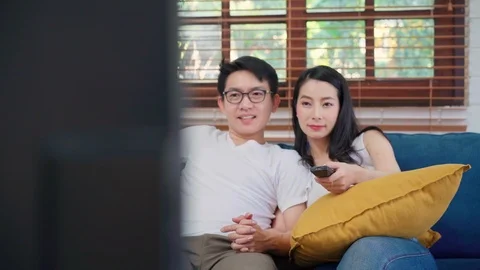 Asian couple watching television in living room at home. Stock Footage