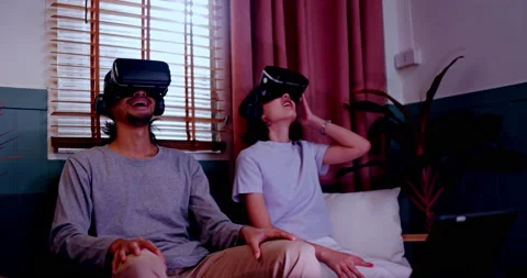 Asian couples wearing modern Virtual reality glasses sit use joystick play games Stock-Footage 171377948