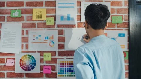 Asian creative man drawing work plan on paper board. Young professional bus.. Stock Photos