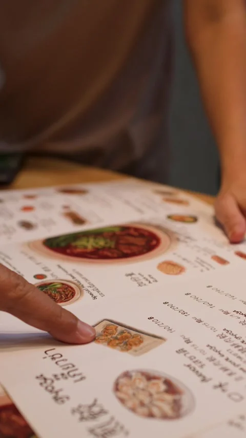 Asian Customers Pointing at Restaurant Menu to Choose and Order Food Stock Footage 345102042