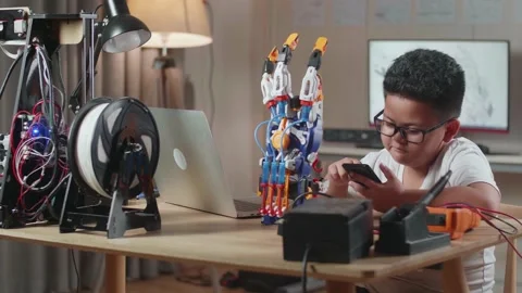 Asian Cute Boy Using Smartphone While Working About A Cyborg Hand On A Laptop Stock Footage 212017369