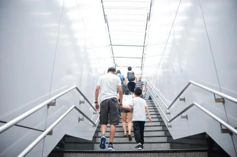 Asian dad and son climb the stairs at MRT Station in Kuala Lumpur, Malaysia. Stock Photos
