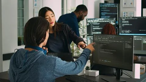Asian database developers analyzing compiling code on multiple screens Stockfoto's