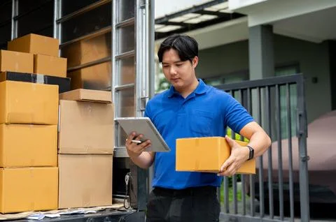 An Asian delivery guy checking the address on his tablet while carrying a p.. Foto stock