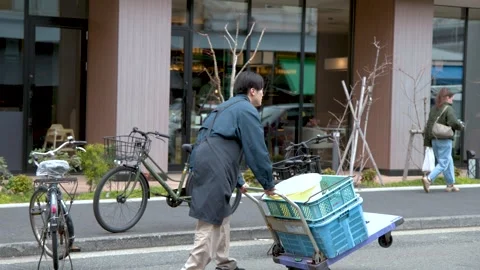 Asian Delivery Worker Pushing Hand Truck with Crates in Tokyo Stock Footage 342574271