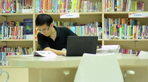 Asian diligent man typing laptop in library Stock Footage 35551260