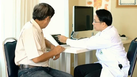 The Asian doctor explaining on tablet to senior man patient Stock Footage 83018443