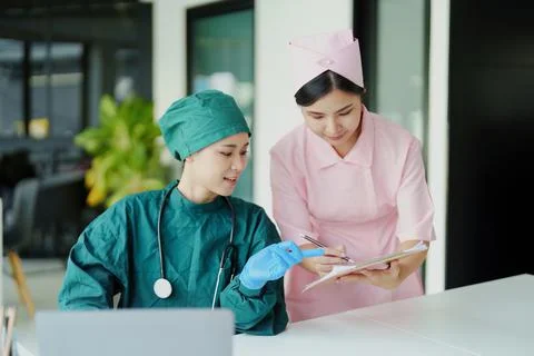 Asian doctors and nurses using computers and documents to view patient Stock Photos