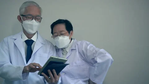 Asian elder doctors man and woman using tablet to customise hospital personal Stock Footage 159421571