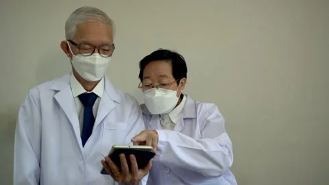 Asian elder doctors man and woman using tablet to customise hospital personal 스톡 동영상 160724185