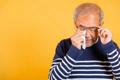Asian elder man crying raise glasses with tissue wipe red eyes Stock Photos