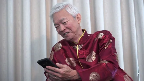 Asian elder man using smartphone call family during Chinese New Year Stock Footage 130711990
