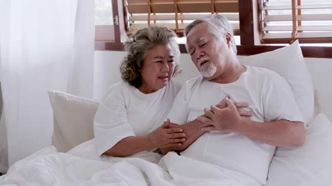 Asian elderly couple in bed, man's heart aches due to heart disease Stock Footage 153786306