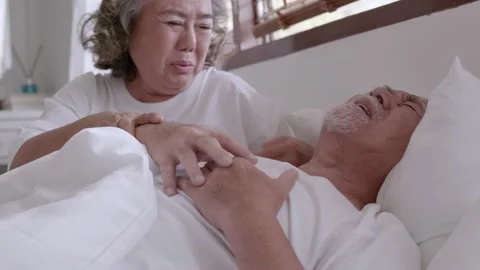 Asian elderly couple in bed, man's heart aches due to heart disease Stock Footage 153786308